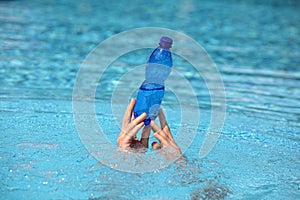 hands holding plastic bottle of water above surface of water