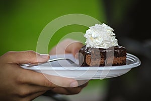 Hands holding plate with chocolate cake amandine