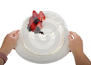 hands holding plate with vanilla frosted buttercream cake with fresh fruit, 