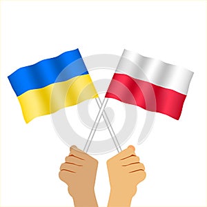 Hands holding Polish  flag and ukrainian flag.