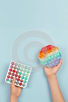 Hands holding pop it fidget toys on blue background. Push pop-it fidgeting game helps relieve stress, anxiety