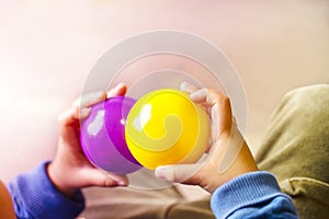 Hands holding purple and yellow two balls