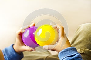 Hands holding purple and yellow two balls