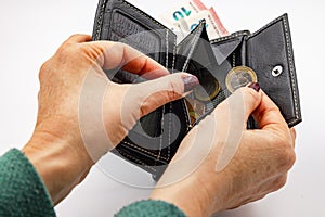 Hands holding a purse with small change and a 2 euro coin isolated in the studio