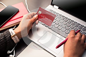 Hands holding a red credit card and using the laptop for make payments online with security. Online shopping concept