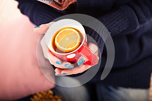 Hands holding a red cup of tea