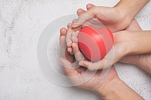 Hands holding a red heart on cement background, CSR or Corporate Social Responsibility