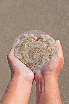 Hands holding a sand in form of heart