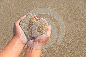 Hands holding a sand in form of heart