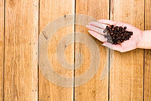 Hands holding scoop of coffee beans, healthy organic food concept on wooden background, top view, copy space for text, close up