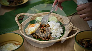 Hands holding silverware eating Thai traditional food, Stir fried minced pork with basil Pad ka prao, rice fried egg serving on