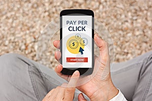 Hands holding smart phone with Pay Per Click concept on screen