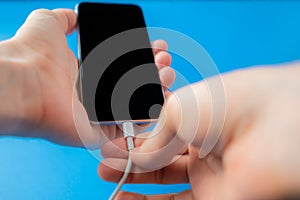 hands holding a smartphone and charging wire, a low battery