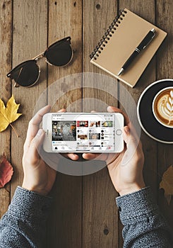 Hands holding a smartphone displaying a social media app interface. The setting