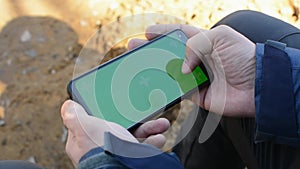 Hands holding a smartphone touching phone with vertical green screen