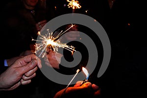 Hands holding sparklers. People lit the sparklers under the chiming clock for the new year photo