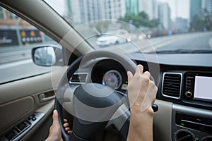 Hands holding steering wheel while driving car