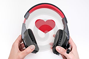 Hands holding stereo headphones and a red heart as a love music concept