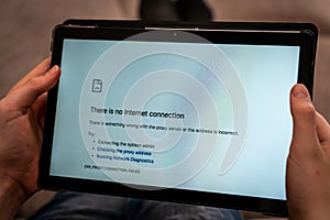 Hands holding tablet with no internet connection screen.