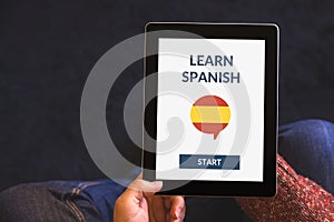 Hands holding tablet with online learn spanish concept on screen