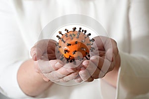 Hands are holding a tangerine with cloves, which looks like a coronavirus, but vitamins strengthen the immune system and cloves