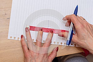 Hands holding taylors measuring tape and pen measuring and tracing on paper