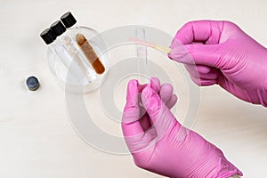 Hands holding test tube and pink indicator paper
