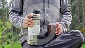 Hands holding thermo and calabash gourd for yerba mate