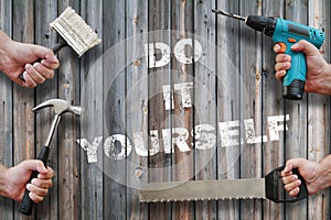 Hands holding tools on wooden background with do it yourself  text on it