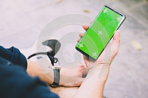 hands holding touching mobile phone with blank copy space on green screen for your text message Selective focus