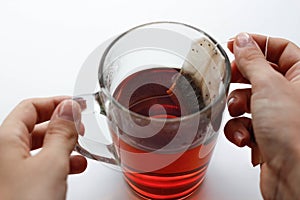 Hands holding transparent glass mug and a tea bag. A Cup of tea.