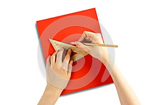 Hands holding a triangular ruler and pencil on a red paper. Closeup