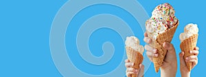 Hands holding a vanilla ice cream cone on blue background. Banner