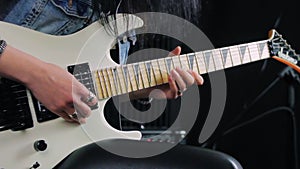 Hands holding a white electric guitar and playing a fast solo