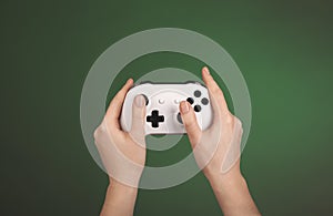 Hands are holding white gamepad against a green background