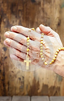 Hands holding wooden rosary