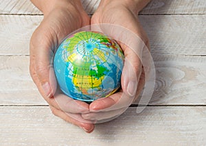 Hands holding world globe on wood