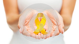 Hands holding yellow gold cancer awareness ribbon