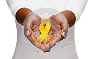 Hands holding yellow gold cancer awareness ribbon