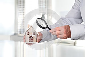 Hands with house and magnifying glass, search home