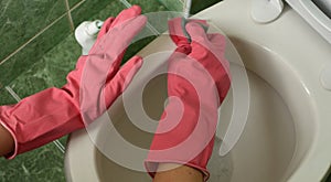 hands in household gloves cleaning the toilet