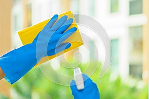 Hands of housekeeper cleaning mirror with yellow cloth.