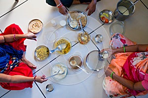 Hands of indian men and women having traditional gujarati thali  lunch on floor for being of low caste