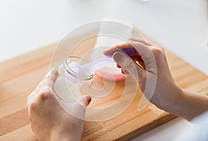 Hands with jar and scoop making formula milk