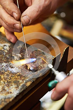 Hands, jewelry and closeup of torch metal for creative art.manufacturing, steel process in workshop. Fingers, expert and