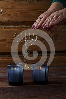 Hands of a Jewish woman over Shabbat candles blessing the light.
