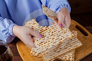 The hands of Jewish women at the Pesach Seder table breaks matzo