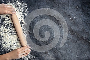 Hands keep rolling pin with flour on a dark background. baking background, banner, menu, recipe place for text, top view