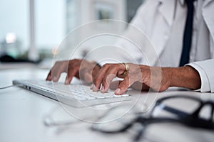 Hands, keyboard and doctor typing at desk for research, healthcare and telehealth on internet in hospital. Computer