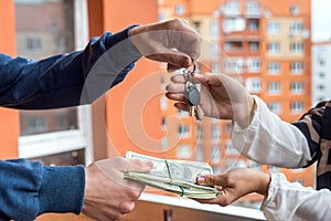 Hands with keys from new apartment and dollar bunch